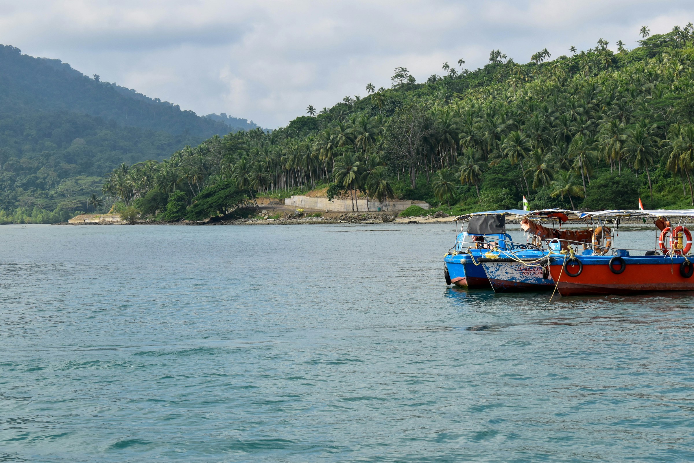 A red and blue boat floating on top of a body of water