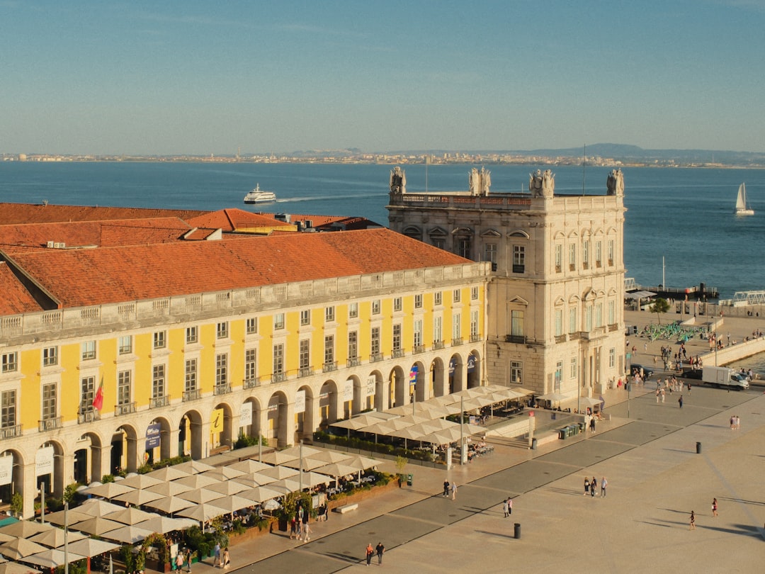 Sunny lisbon square with historic buildings and river.