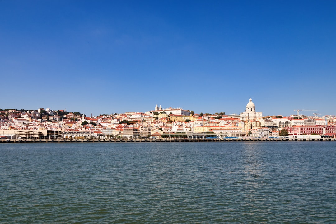 Cityscape overlooking a wide river under a clear blue sky.