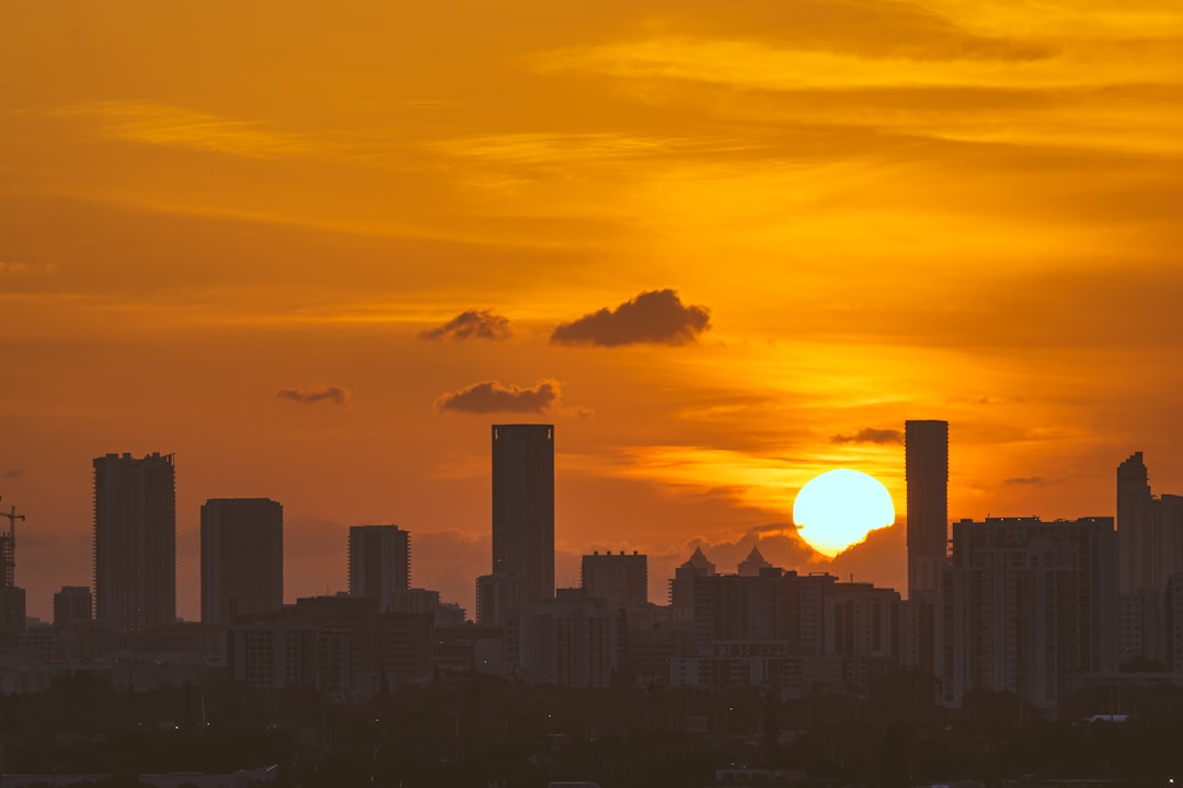 the sun is setting over a city with tall buildings