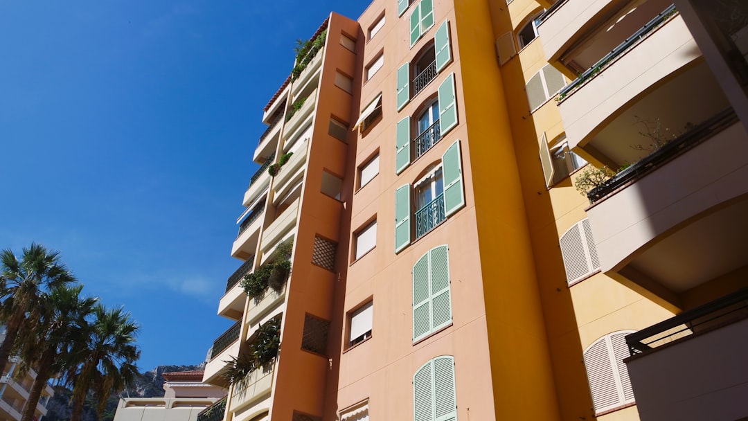 a tall orange building with palm trees in the background