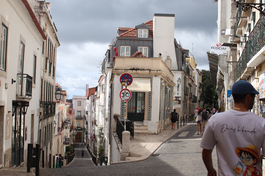 Steep cobblestone street lined with buildings under cloudy sky.