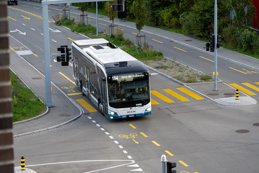 A modern electric bus driving through a city intersection.